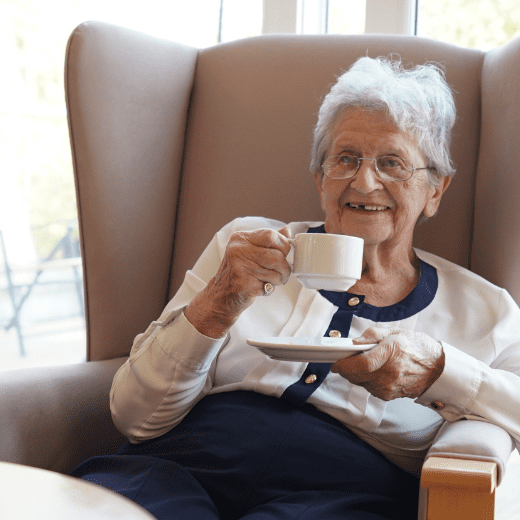 ACI Care | A resident sitting comfortably, enjoying a cup of tea or coffee, receiving compassionate Dementia Care