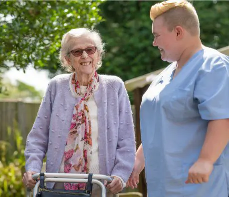 ACI Care | one of our residents outside walking with a member of staff smiling