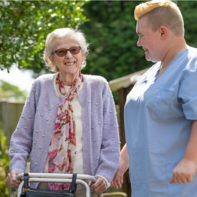 ACI Care | one of our residents outside walking with a member of staff smiling