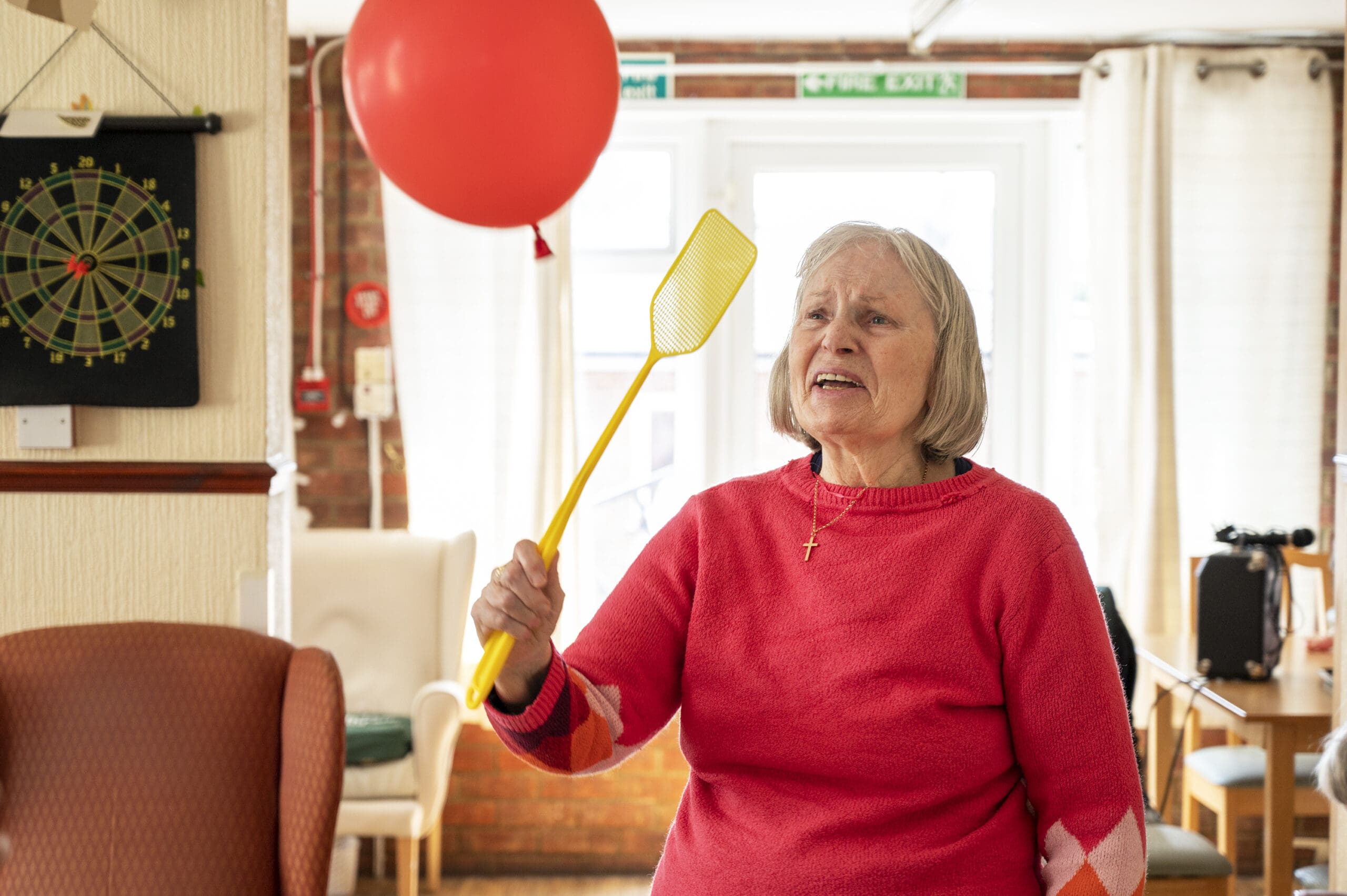 A resident hitting a balloon with a yellow swatter