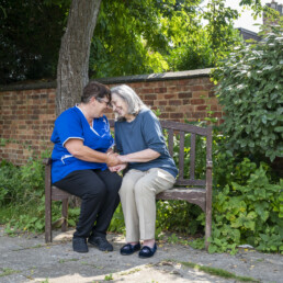 Bespoke Care | A resident and care worker sitting on a bench